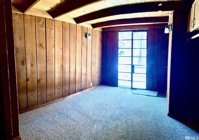 unfurnished room featuring carpet floors, wooden ceiling, beamed ceiling, and wood walls