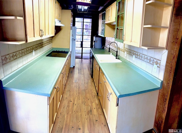 kitchen featuring sink, white refrigerator, black electric cooktop, light hardwood / wood-style floors, and backsplash