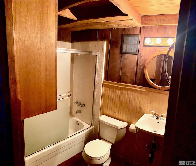 full bathroom featuring sink, toilet, combined bath / shower with glass door, and wood walls