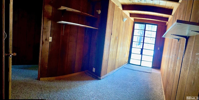 hall with wooden walls, beam ceiling, carpet, and wooden ceiling