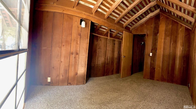 interior space featuring vaulted ceiling, carpet, and wood walls