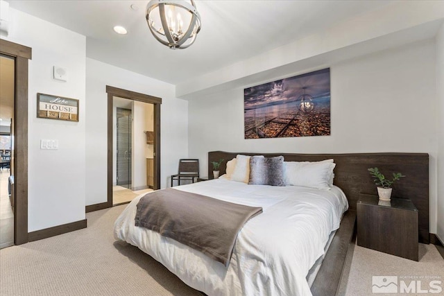 carpeted bedroom featuring a notable chandelier and ensuite bath