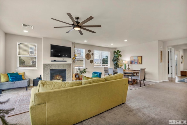 living room featuring ceiling fan, a fireplace, and light carpet