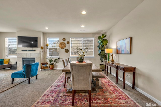 dining space with a tiled fireplace, carpet, and a wealth of natural light