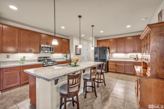 kitchen featuring sink, hanging light fixtures, stainless steel appliances, a kitchen breakfast bar, and an island with sink