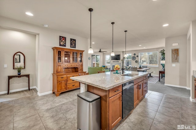 kitchen featuring pendant lighting, dishwasher, sink, a kitchen island with sink, and light stone countertops