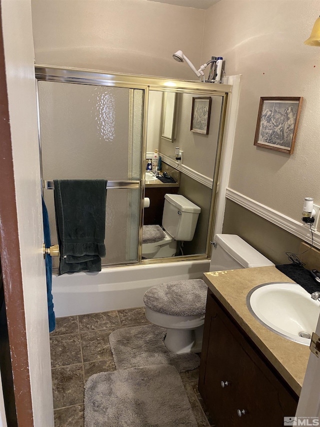 full bathroom with enclosed tub / shower combo, vanity, and toilet