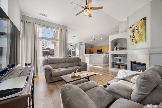 living room with ceiling fan, lofted ceiling, and light hardwood / wood-style flooring