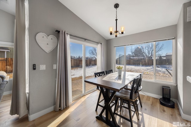 dining room featuring vaulted ceiling, a notable chandelier, and light hardwood / wood-style flooring