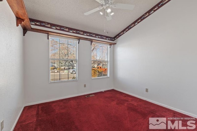 carpeted empty room with beamed ceiling, ceiling fan, and a textured ceiling