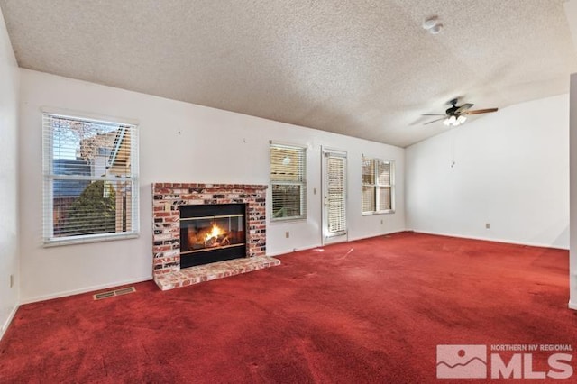 unfurnished living room featuring vaulted ceiling, a fireplace, carpet, ceiling fan, and a textured ceiling