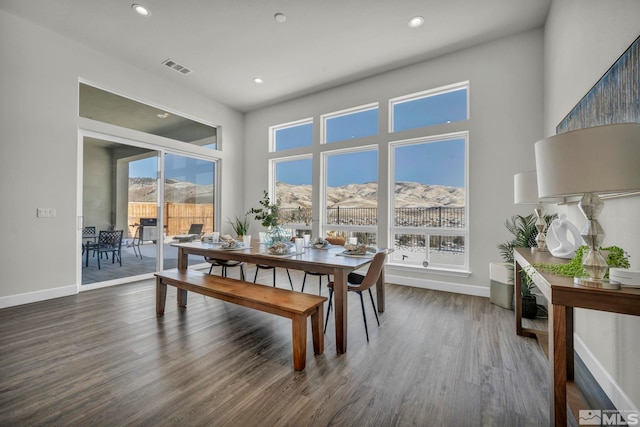 dining area featuring dark hardwood / wood-style flooring, a mountain view, and a high ceiling