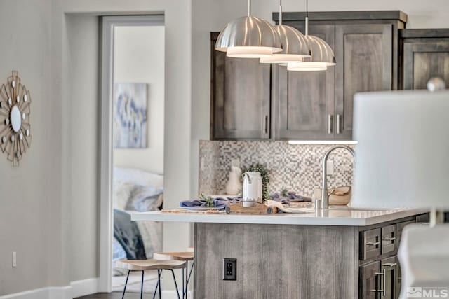 kitchen featuring sink, backsplash, a kitchen bar, decorative light fixtures, and kitchen peninsula