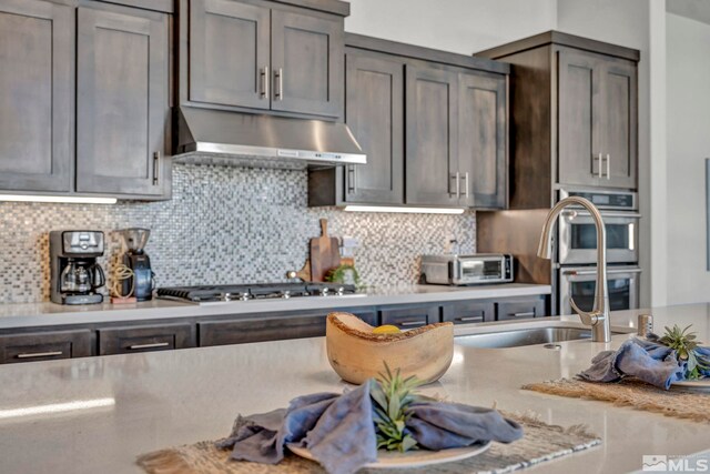 kitchen featuring light stone counters, decorative backsplash, and stainless steel appliances