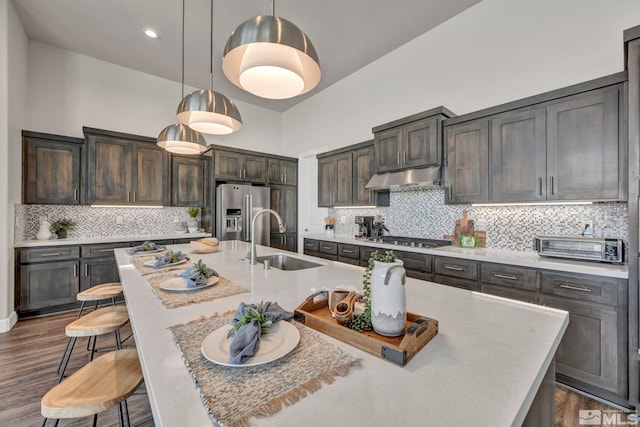 kitchen featuring appliances with stainless steel finishes, sink, a kitchen island with sink, and decorative light fixtures