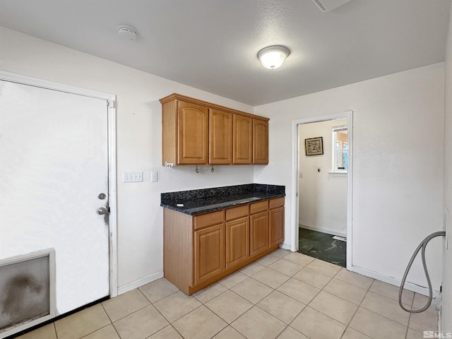 kitchen featuring light tile patterned floors, a textured ceiling, and dark stone countertops