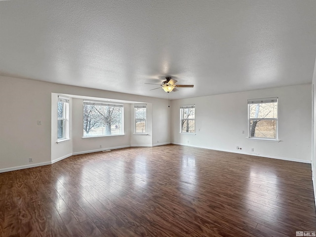 unfurnished living room featuring ceiling fan, plenty of natural light, dark hardwood / wood-style flooring, and a textured ceiling