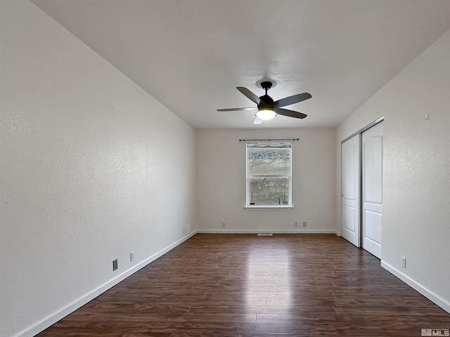 empty room featuring dark wood-type flooring and ceiling fan