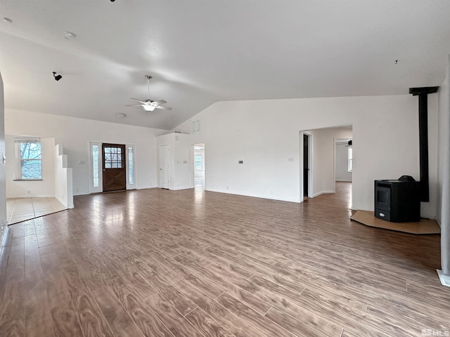 unfurnished living room featuring lofted ceiling, hardwood / wood-style floors, ceiling fan, and a wood stove