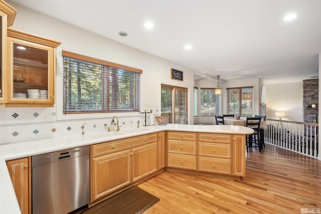 kitchen featuring sink, decorative backsplash, stainless steel dishwasher, kitchen peninsula, and light wood-type flooring