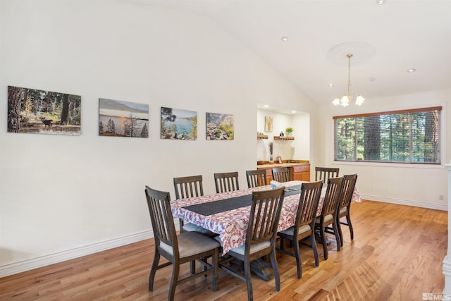 dining space featuring high vaulted ceiling, light hardwood / wood-style floors, and a notable chandelier