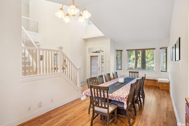 dining area featuring a towering ceiling, a notable chandelier, and light hardwood / wood-style floors