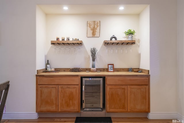 bar with beverage cooler and light hardwood / wood-style floors