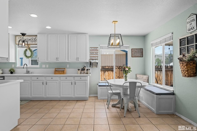 kitchen with white cabinetry, hanging light fixtures, light tile patterned floors, and a notable chandelier