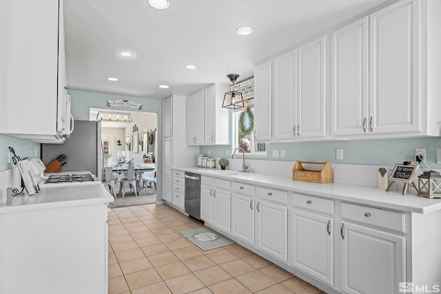 kitchen with light tile patterned flooring, appliances with stainless steel finishes, sink, white cabinets, and hanging light fixtures