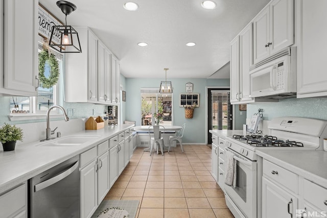 kitchen featuring white appliances, decorative light fixtures, and white cabinets