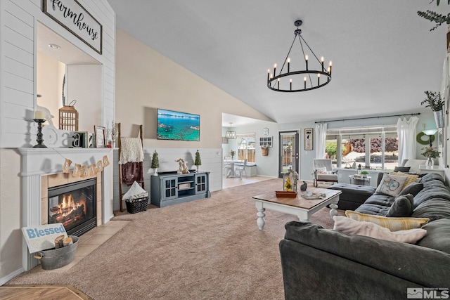 living room with a tiled fireplace, a notable chandelier, and high vaulted ceiling