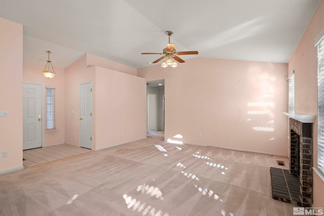 unfurnished living room featuring vaulted ceiling, a brick fireplace, light carpet, and ceiling fan