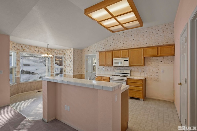 kitchen with an inviting chandelier, tile countertops, decorative light fixtures, vaulted ceiling, and white appliances