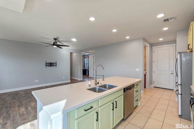 kitchen featuring sink, green cabinets, ceiling fan, stainless steel appliances, and a kitchen island with sink