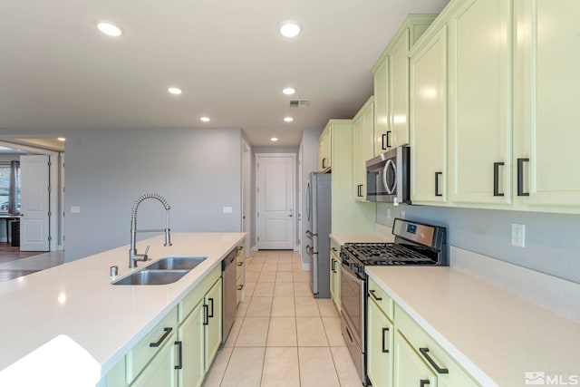 kitchen featuring appliances with stainless steel finishes, sink, light tile patterned floors, and green cabinets