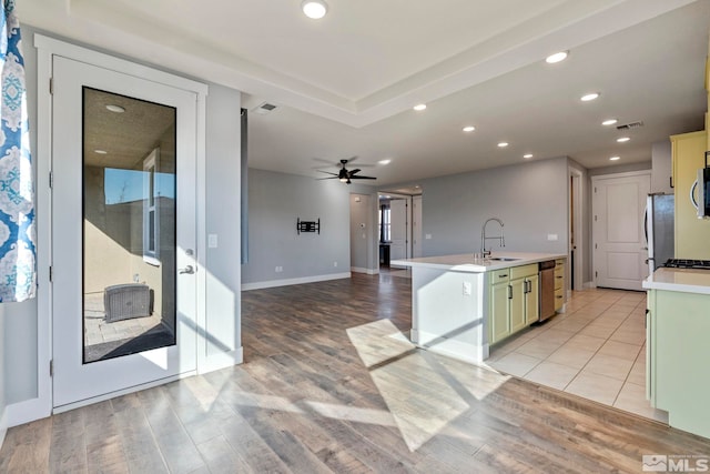 kitchen with a kitchen island with sink, sink, light hardwood / wood-style floors, and appliances with stainless steel finishes