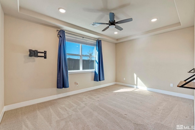 unfurnished room featuring a tray ceiling, carpet floors, and ceiling fan