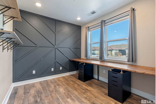 unfurnished office featuring hardwood / wood-style flooring, built in desk, and a mountain view