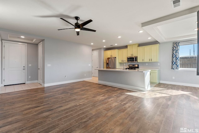 kitchen featuring appliances with stainless steel finishes, a kitchen island with sink, sink, and light hardwood / wood-style flooring