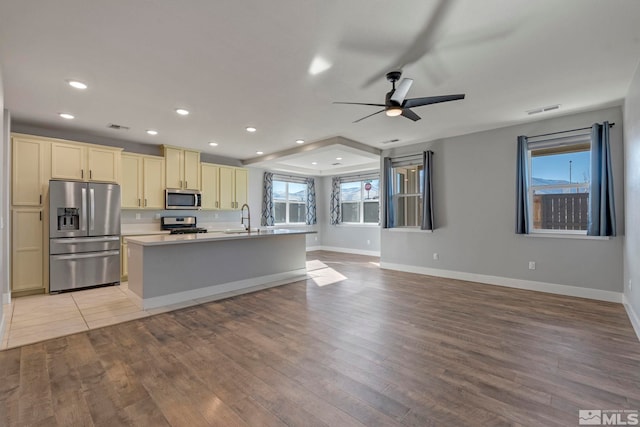 kitchen featuring sink, light hardwood / wood-style flooring, a kitchen island with sink, stainless steel appliances, and cream cabinetry