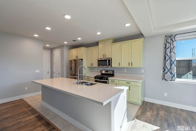 kitchen featuring appliances with stainless steel finishes, sink, a kitchen island with sink, and light wood-type flooring