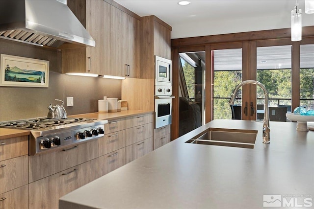 kitchen with sink, extractor fan, wall oven, hanging light fixtures, and stainless steel gas stovetop