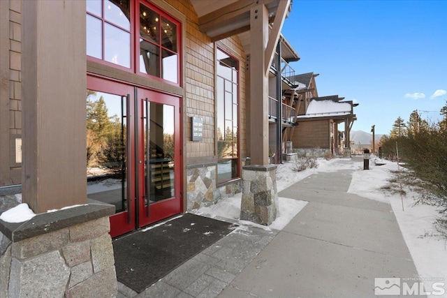 snow covered property entrance featuring french doors