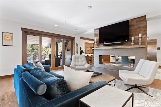 living room with a multi sided fireplace and wood-type flooring