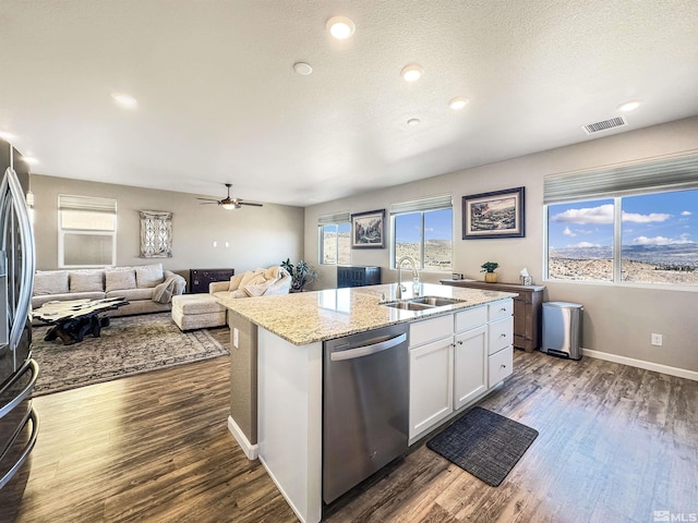 kitchen with white cabinetry, sink, dark hardwood / wood-style flooring, stainless steel appliances, and a center island with sink