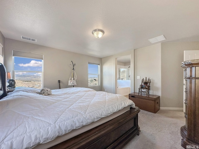 bedroom with light carpet, connected bathroom, multiple windows, and a textured ceiling