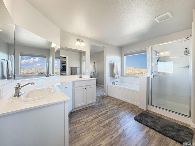 bathroom featuring hardwood / wood-style flooring, vanity, a textured ceiling, and plus walk in shower