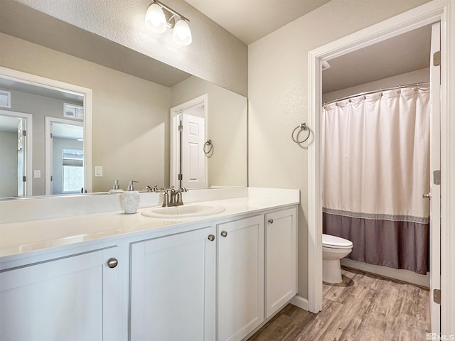 bathroom with walk in shower, vanity, toilet, and hardwood / wood-style floors