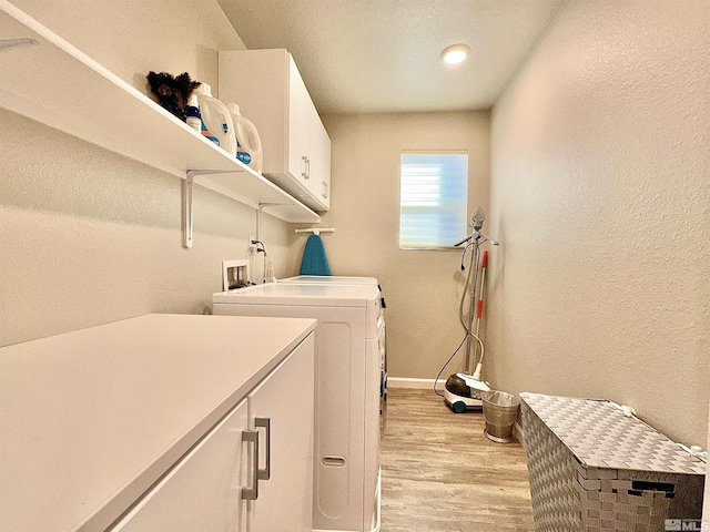 laundry area featuring cabinets, light wood-type flooring, and washer and clothes dryer