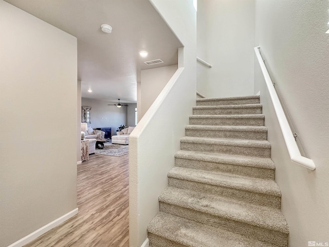 staircase featuring hardwood / wood-style floors and ceiling fan